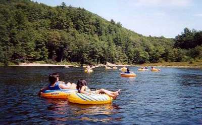 people floating down a calm river in yellow and blue inner tubes on a sunny day