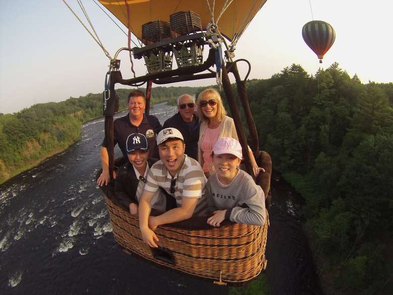 people in a hot air balloon flying over a river