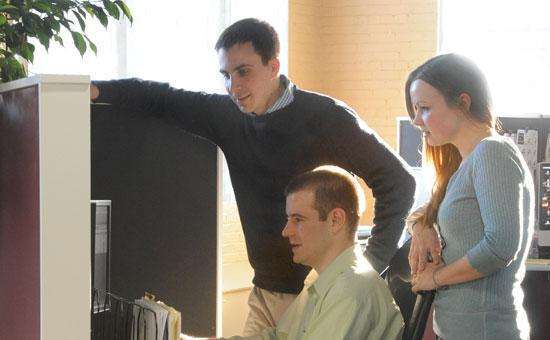 three people looking down at a computer screen