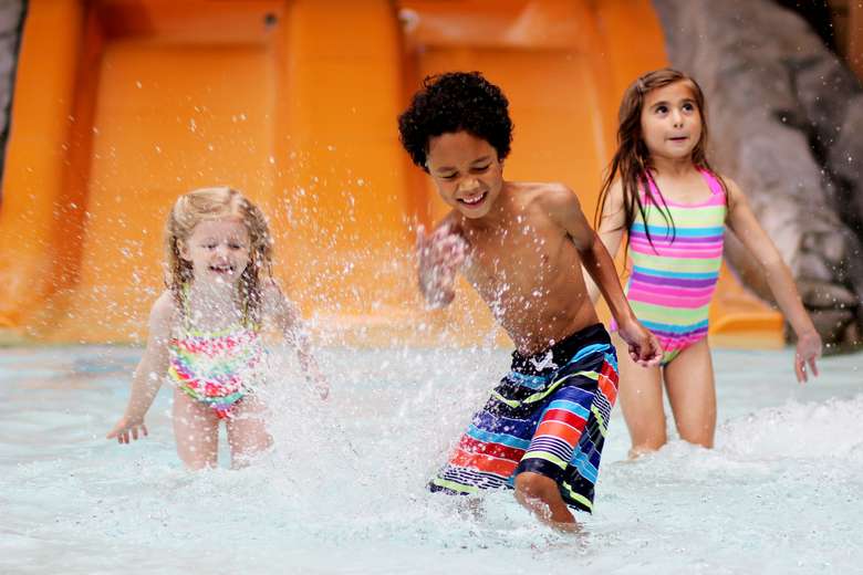 three kids splashing around in an indoor waterpark