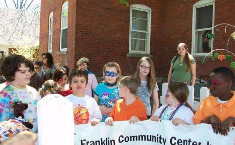 kids with their faces painted holding up a franklin community center banner outside the building