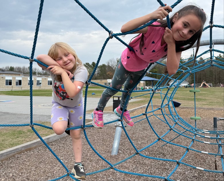 two kids on a playground climbing structure