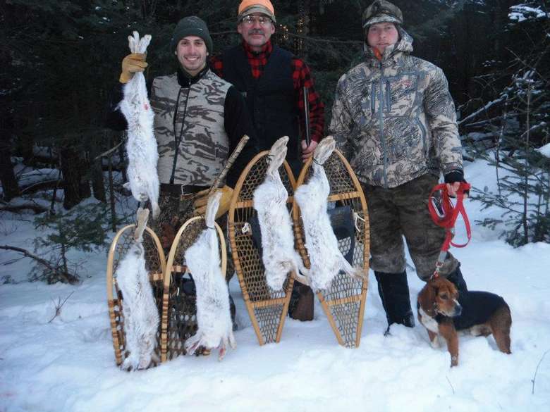 three hunters and a dog displaying five rabbits
