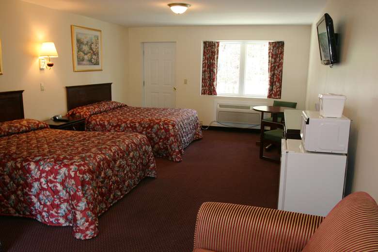 two beds in a guest room with red blankets, and a window is in the back
