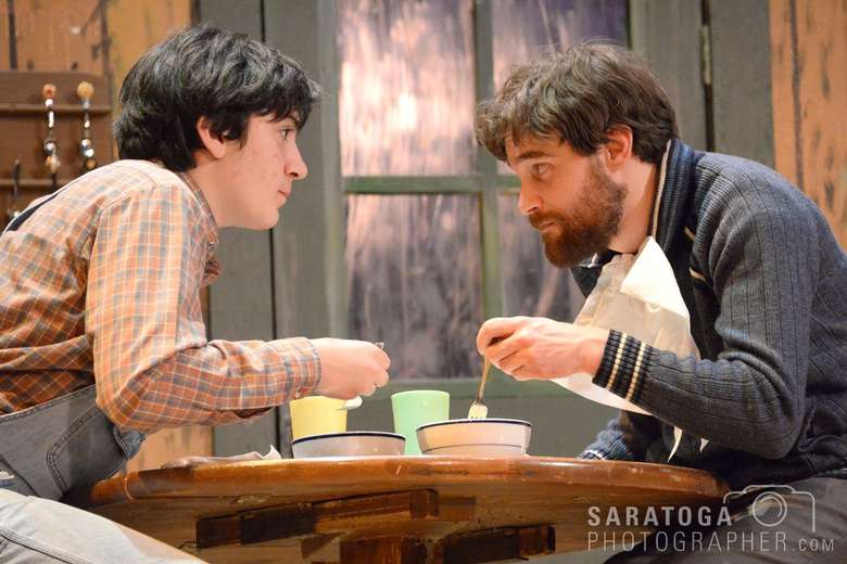 two actors eating out of bowls on stage