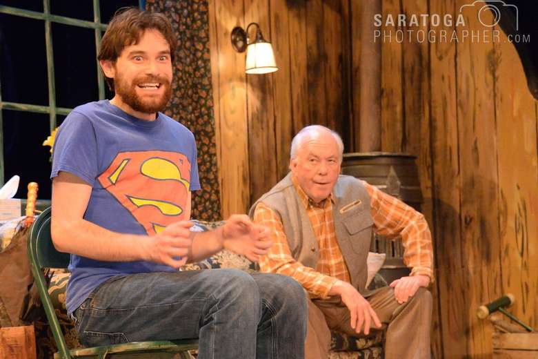 man in a superman t-shirt looking excited while an old man looks on