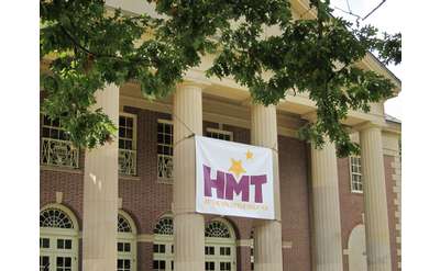 exterior of the spa little theater with an HMT banner attached to two of its tall columns