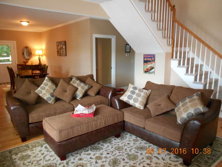 two couches with a large bench. There are stairs to the right and the dining area is in back.