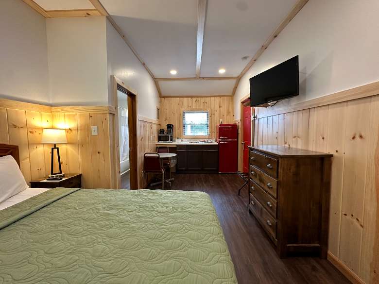 Pet friendly cabin interior with bed, kitchen, dresser, and table