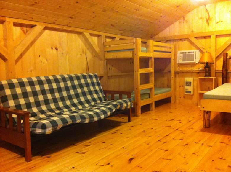 a futon in a camping cabin with a bunk bed nearby