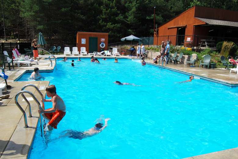 a large outdoor pool with bright blue water and people swimming
