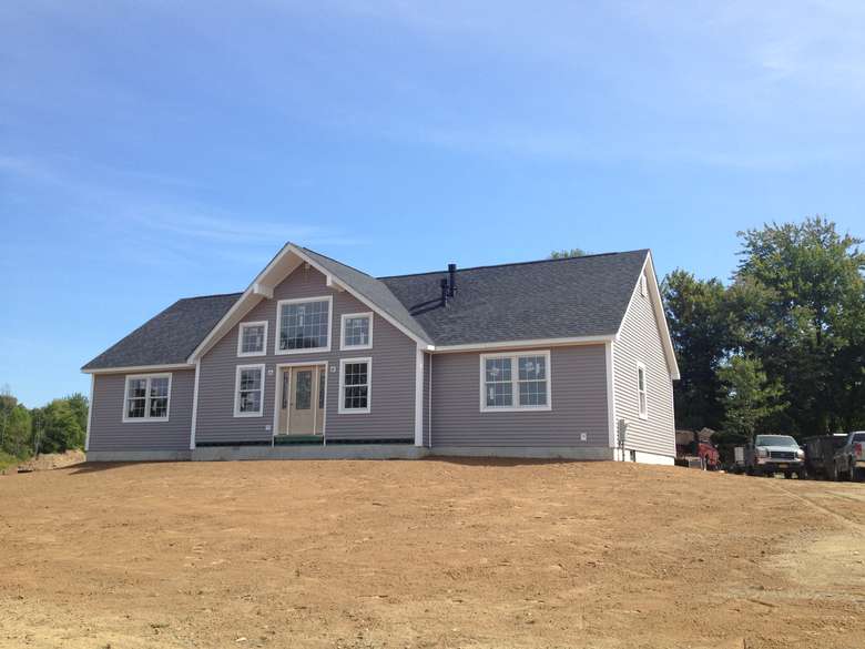 newly built house with purple siding on a dirt lot