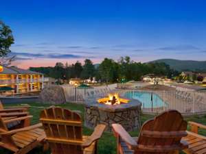 a fire pit with chairs and an outdoor pool at evening