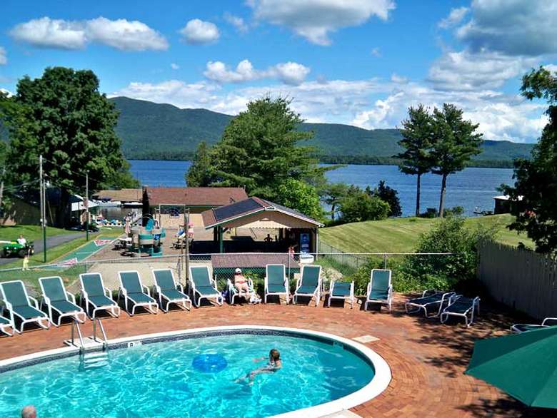 outdoor circular pool surrounded by chairs, lake nearby