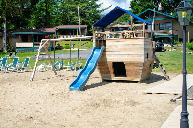 playground with swings and a slide on a sandy area