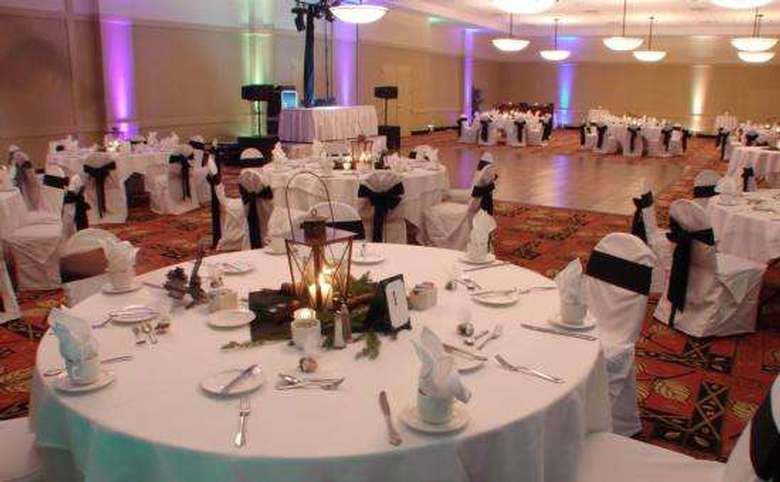 hotel ballroom set for a wedding with white tablecloths and chair covers