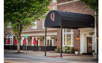 black awning with a red Q on it in front of an entrance to the queensbury hotel