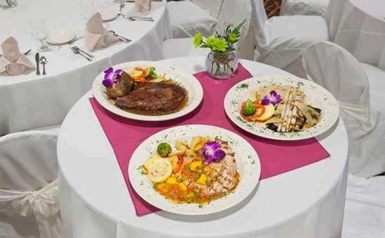 beautiful plated food on a small round table with a white and pink tablecloth