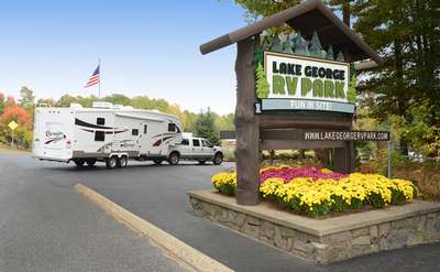 the sign for lake george rv park with a rv in the back