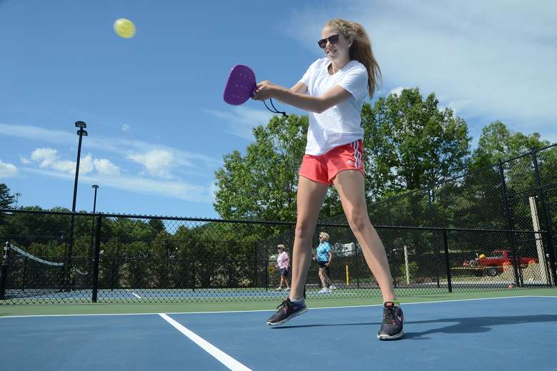 a woman playing pickleball on a court