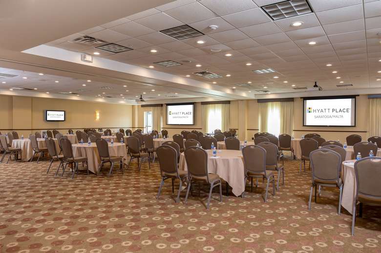 large room set up in a banquet style with individual round tables set with linens