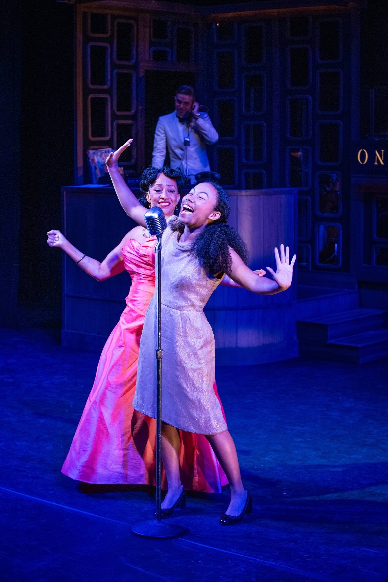two women sing on stage