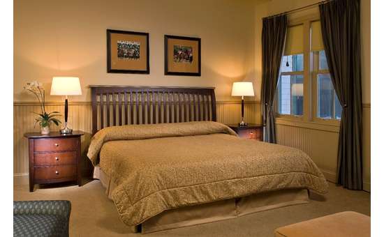 hotel room with king-sized bed, large window, nightstands on either side, pictures on wall