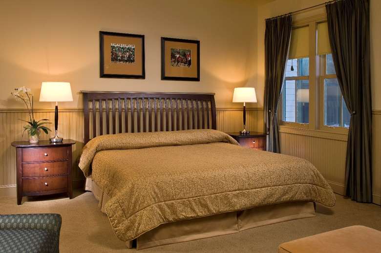 hotel room with king-sized bed, large window, nightstands on either side, pictures on wall