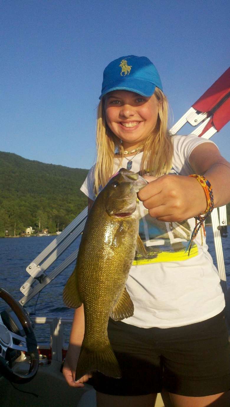 A girl with a blue baseball cap holding a bass