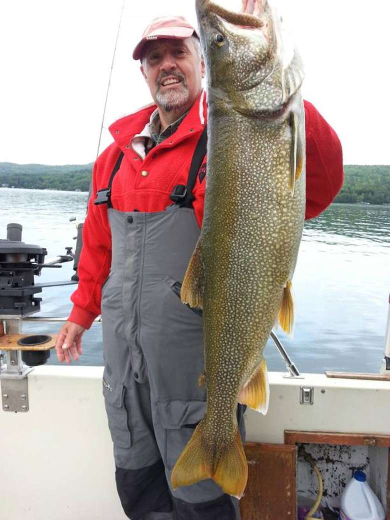 A man in a boat holding a huge lake trout
