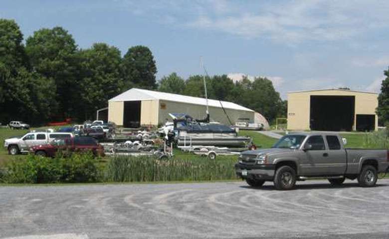 cars with boat trailers located on a grassy field near the road