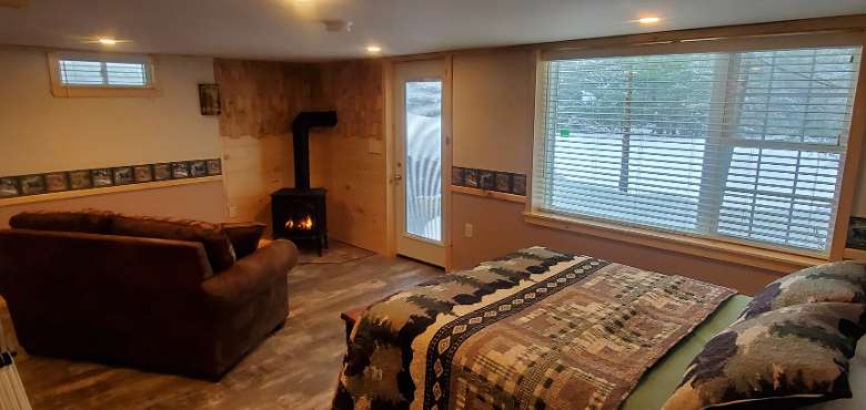 cabin with couch, bed, and fire in fireplace