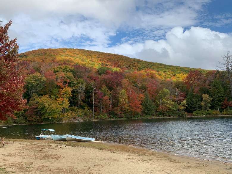beach with a couple boats, mountain with fall foliage