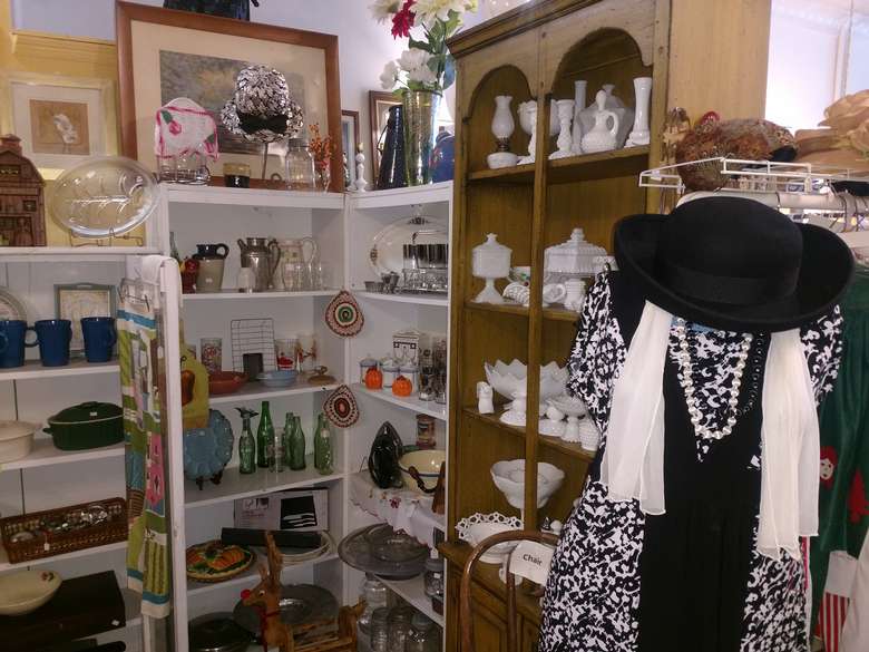 some vintage clothing on display and antique glassware on shelves
