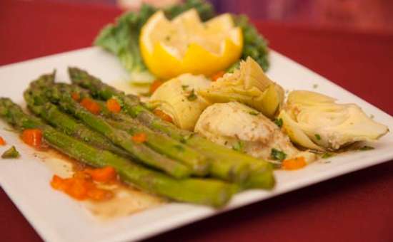 plate of fresh bright green asparagus served with artichoke hearts and a lemon cut into a flower