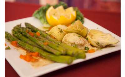 plate of fresh bright green asparagus served with artichoke hearts and a lemon cut into a flower