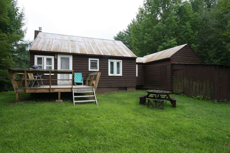 the back fo the cabin with a back deck and picnic table