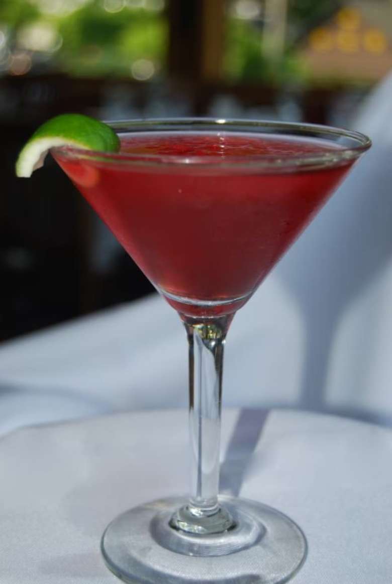 red cocktail with a lime garnish