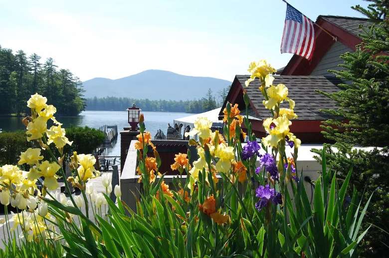 view of flowers, a restaurant, and a lake and mountains in the distance