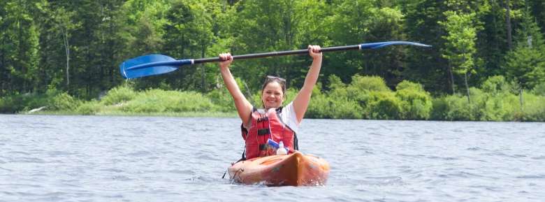woman kayaking, holding up paddles