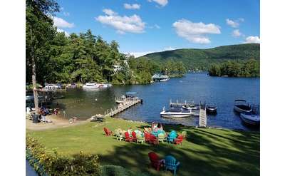 somewhat aerial view of colorful lawn chairs, water, dock, boat, mountains