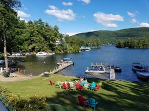 somewhat aerial view of colorful lawn chairs, water, dock, boat, mountains