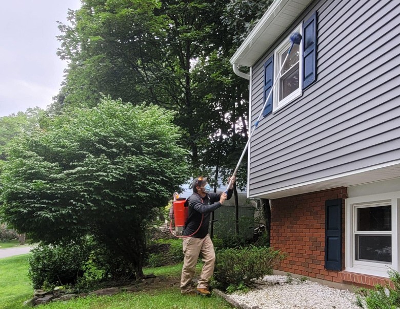 man doing pest control on a house