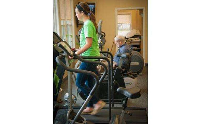 Girl on treadmill with man in the background on a machine