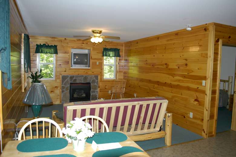 inside a cottage with a futon, tables and chairs, fireplace