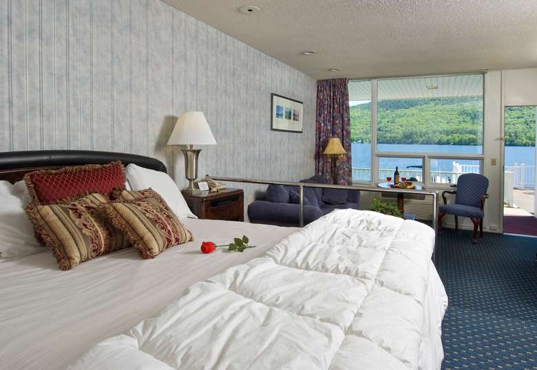 king-sized bed and seating area in a room overlooking lake george