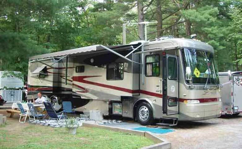 a rv with a person sitting in a chair right outside of it