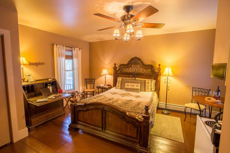 bedroom with wooden queen bed, writing desk, lamps and ceiling fan