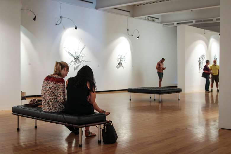 visitors on a bench inside an art gallery space