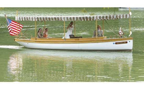 the electric boat with canopy out on the water passing by with the bride waving